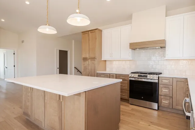 a large kitchen with stainless steel appliances a stove a sink a dining table and chairs