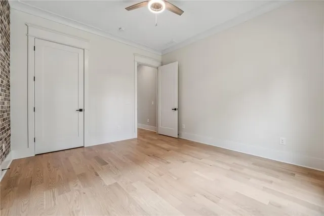 a spacious bedroom with a bed a table and potted plant with the wooden floor