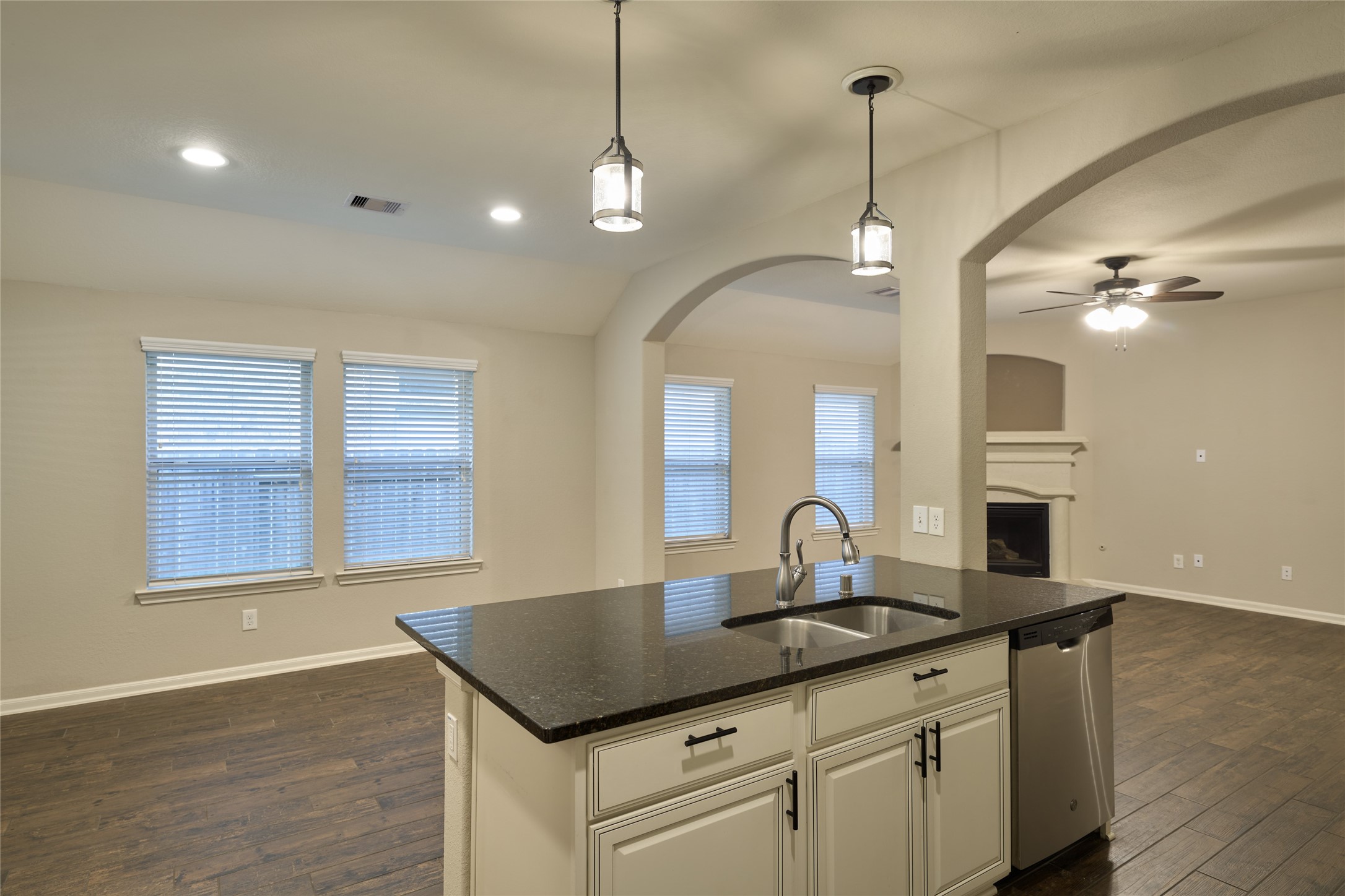 116 Fox Trail Road Montgomery, TX 77316 - Photo 22 of 50 The kitchen island features a sink and pendant lighting. An archway leads to a cozy living area with a fireplace, ideal for entertaining or family gatherings.