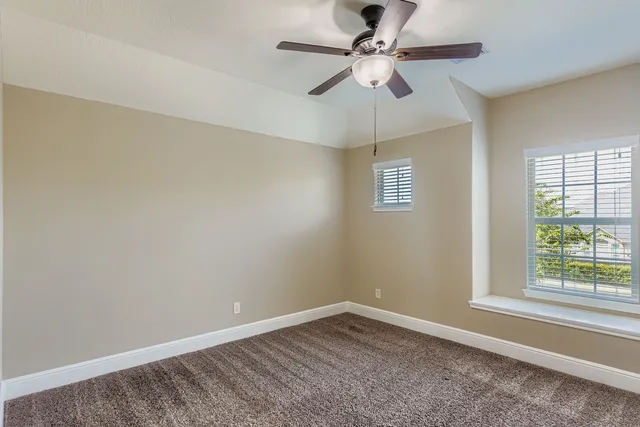 an empty room with a window and a fan