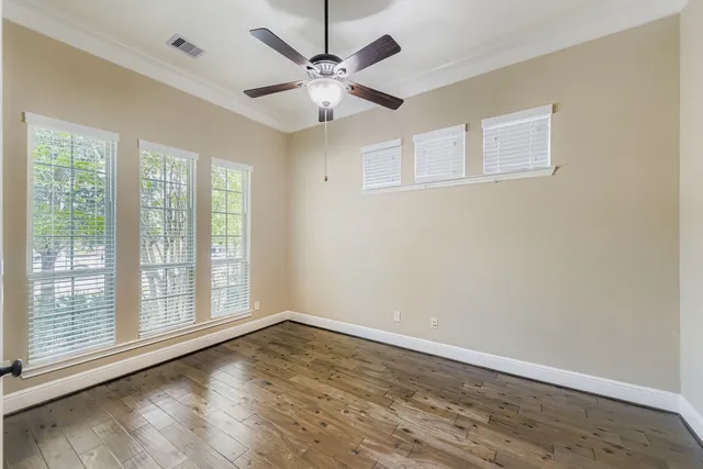 a view of an empty room with wooden floor and a window