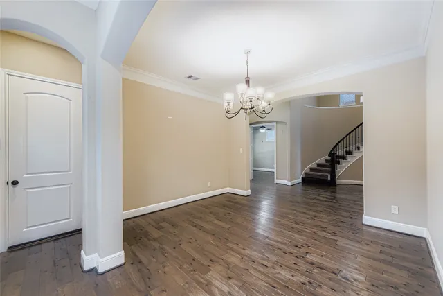 a view of a room with wooden floor staircase and a chandelier