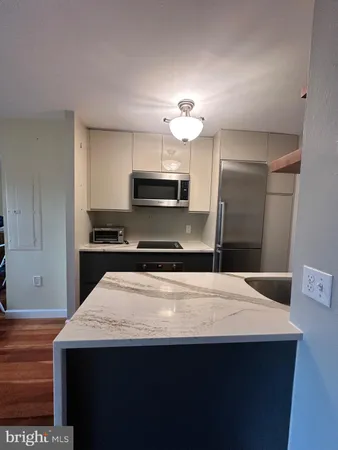 a kitchen with kitchen island a sink dishwasher a stove and a refrigerator with wooden floor