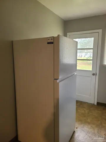 a view of a refrigerator in kitchen and an empty room