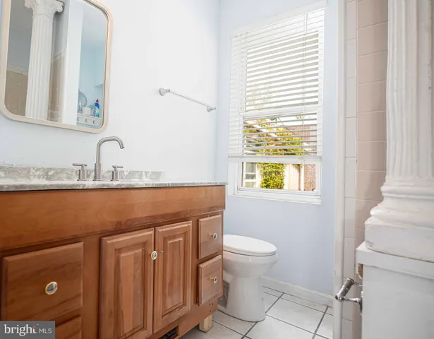 a bathroom with a granite countertop sink toilet and mirror