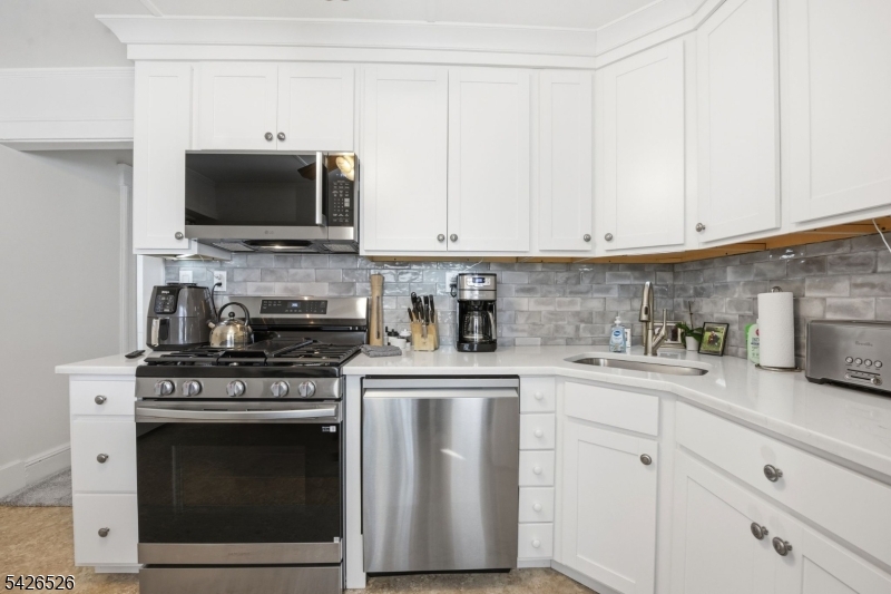 39 Wilmore Road, Unit 2 Little Falls, NJ 07424 - Photo 7 of 14 a kitchen with stainless steel appliances granite countertop a stove a sink and white cabinets