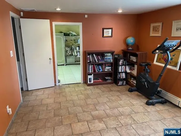 a view of an empty room with bookshelf and a window