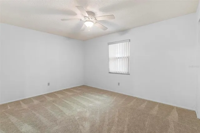 an empty room with windows and fan