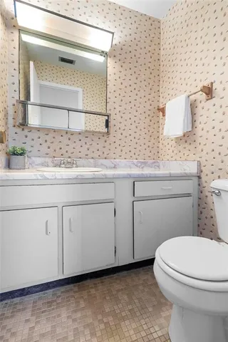 a bathroom with a granite countertop toilet sink and mirror