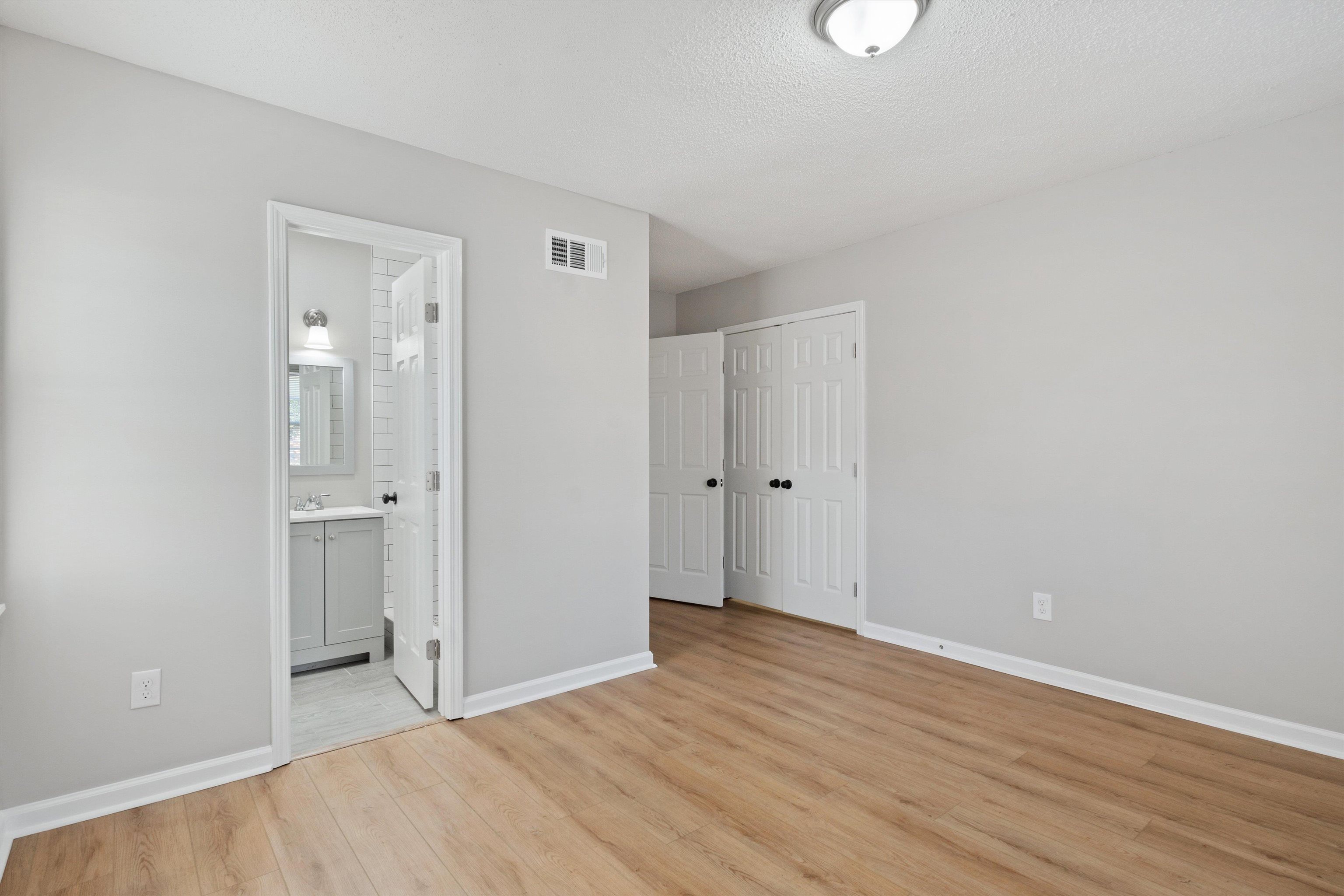 4487 East Dearing Road Memphis, TN 38117 - Photo 16 of 27 Unfurnished bedroom featuring light wood finished floors, a textured ceiling, a closet, and ensuite bathroom
