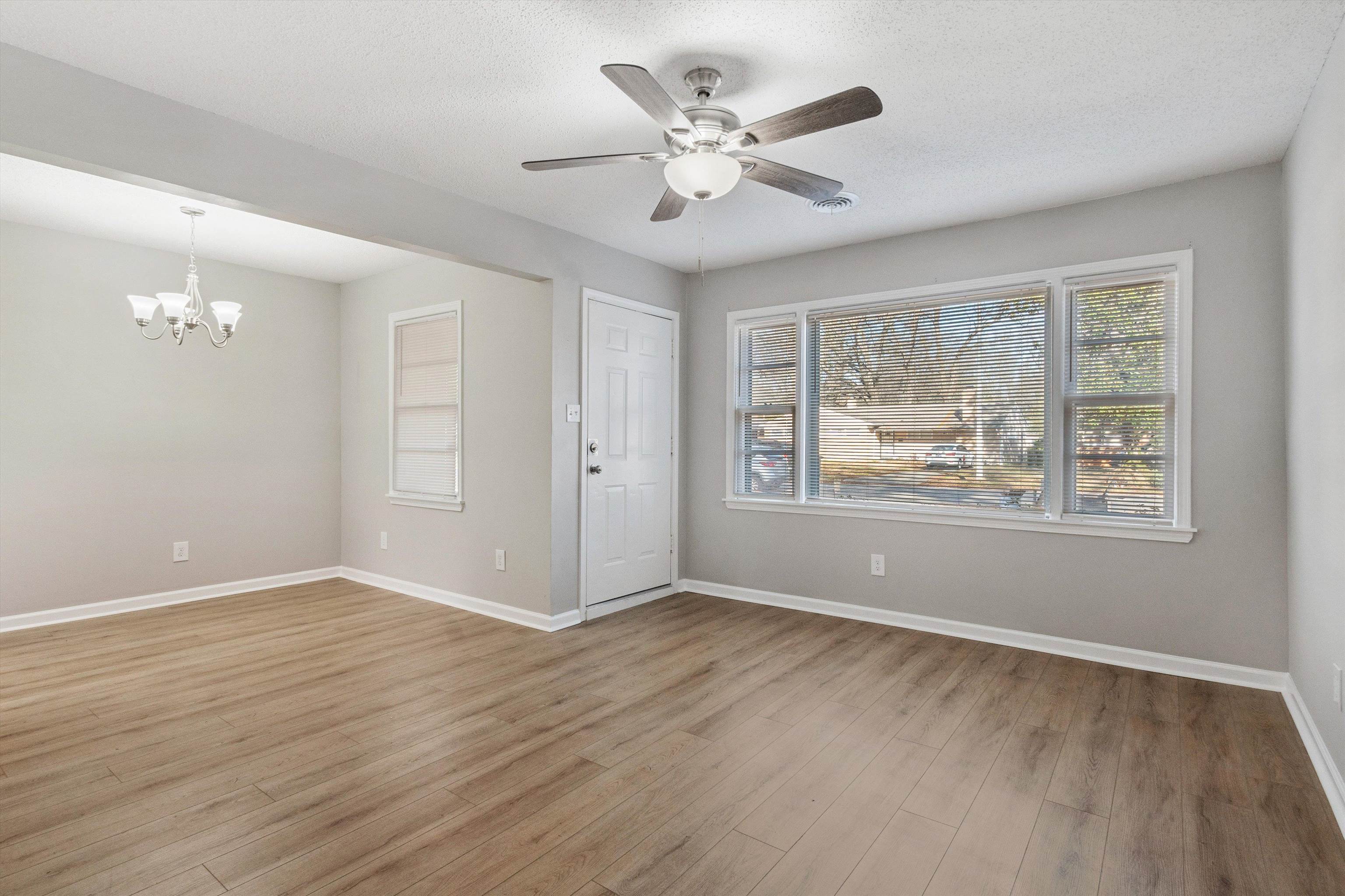 4487 East Dearing Road Memphis, TN 38117 - Photo 5 of 27 Empty room featuring light wood-style flooring, a ceiling fan, a chandelier, and a textured ceiling