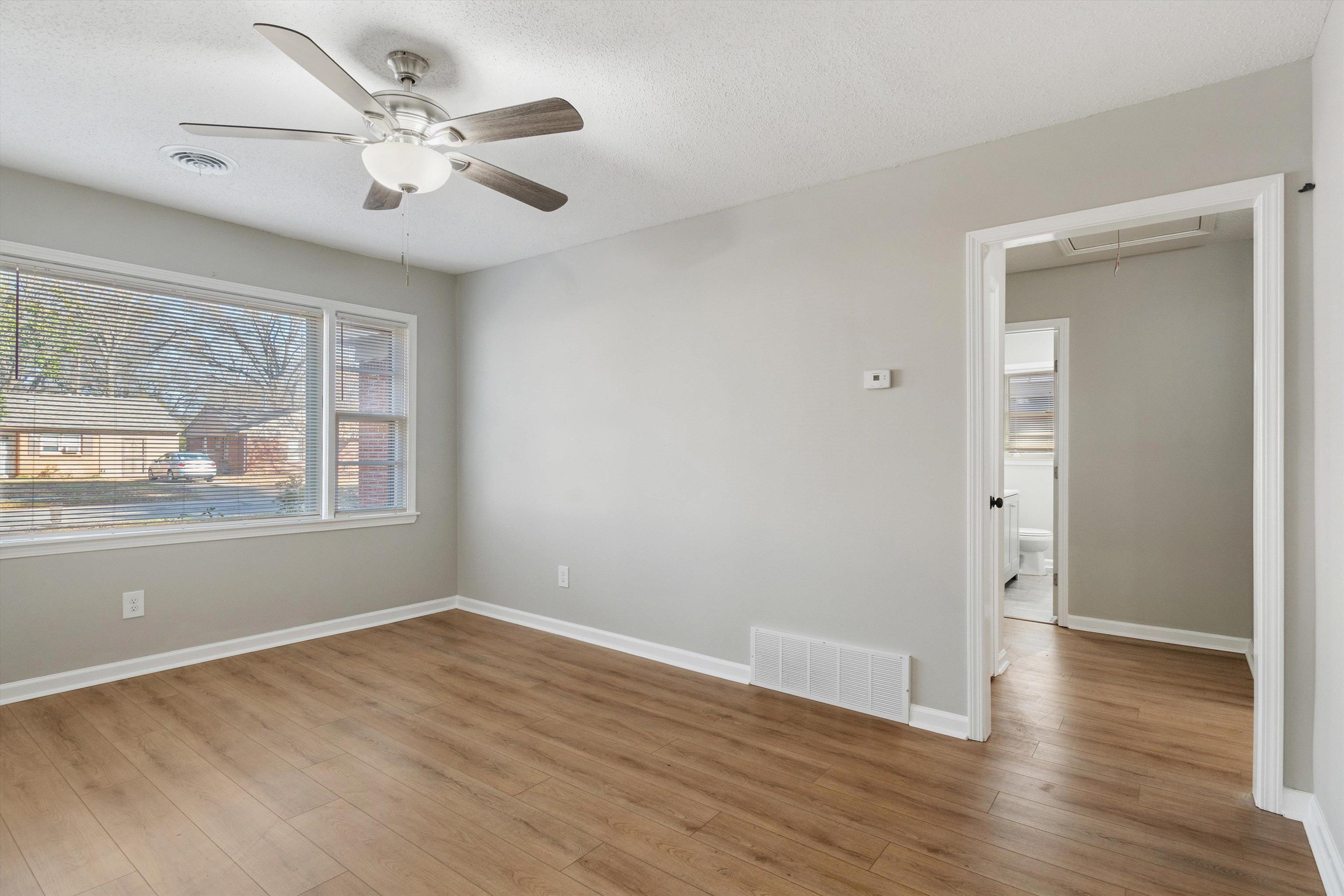 4487 East Dearing Road Memphis, TN 38117 - Photo 6 of 27 Empty room with attic access, wood finished floors, a ceiling fan, and a textured ceiling