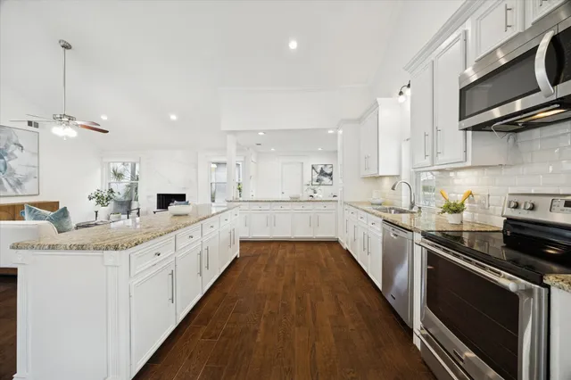 a large kitchen with stainless steel appliances kitchen island granite countertop a sink and cabinets