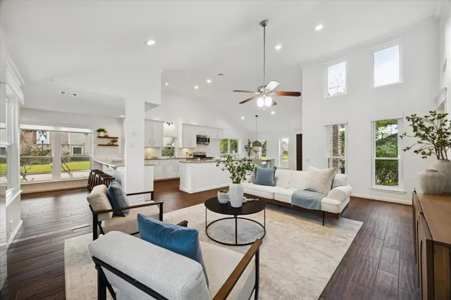 a living room with furniture kitchen view and a wooden floor