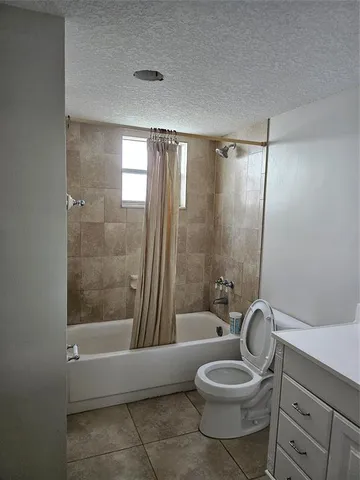 a bathroom with a granite countertop bathtub shower sink vanity and toilet