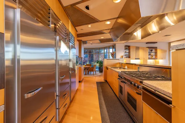 a kitchen with stainless steel appliances kitchen island granite countertop a table chairs in it and a wooden floor