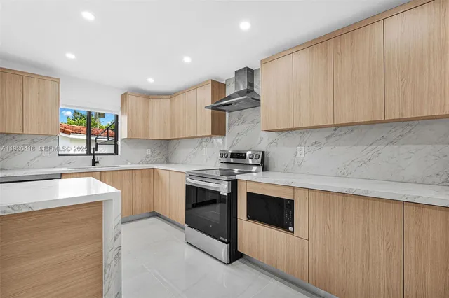 a kitchen with stainless steel appliances granite countertop a refrigerator a sink a stove and white cabinets