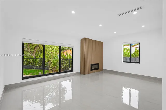a view of an empty room with a fireplace and window