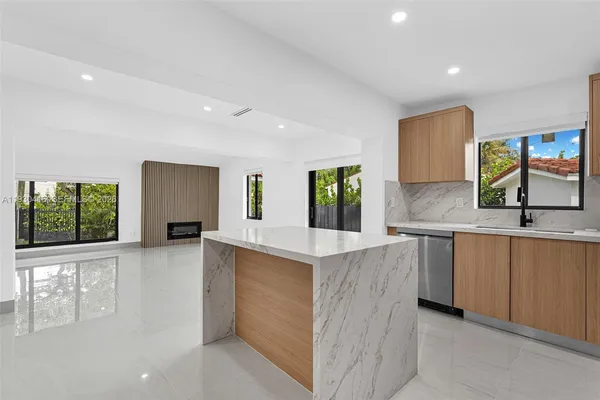 a kitchen with stainless steel appliances granite countertop a refrigerator a sink a stove and white cabinets