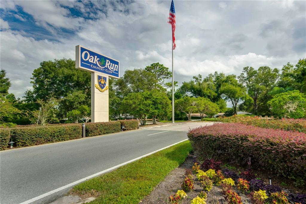 8156 Southwest 108th Ln Road Ocala, FL 34481 - Photo 36 of 50 a sign board with flower plants and tree in the background