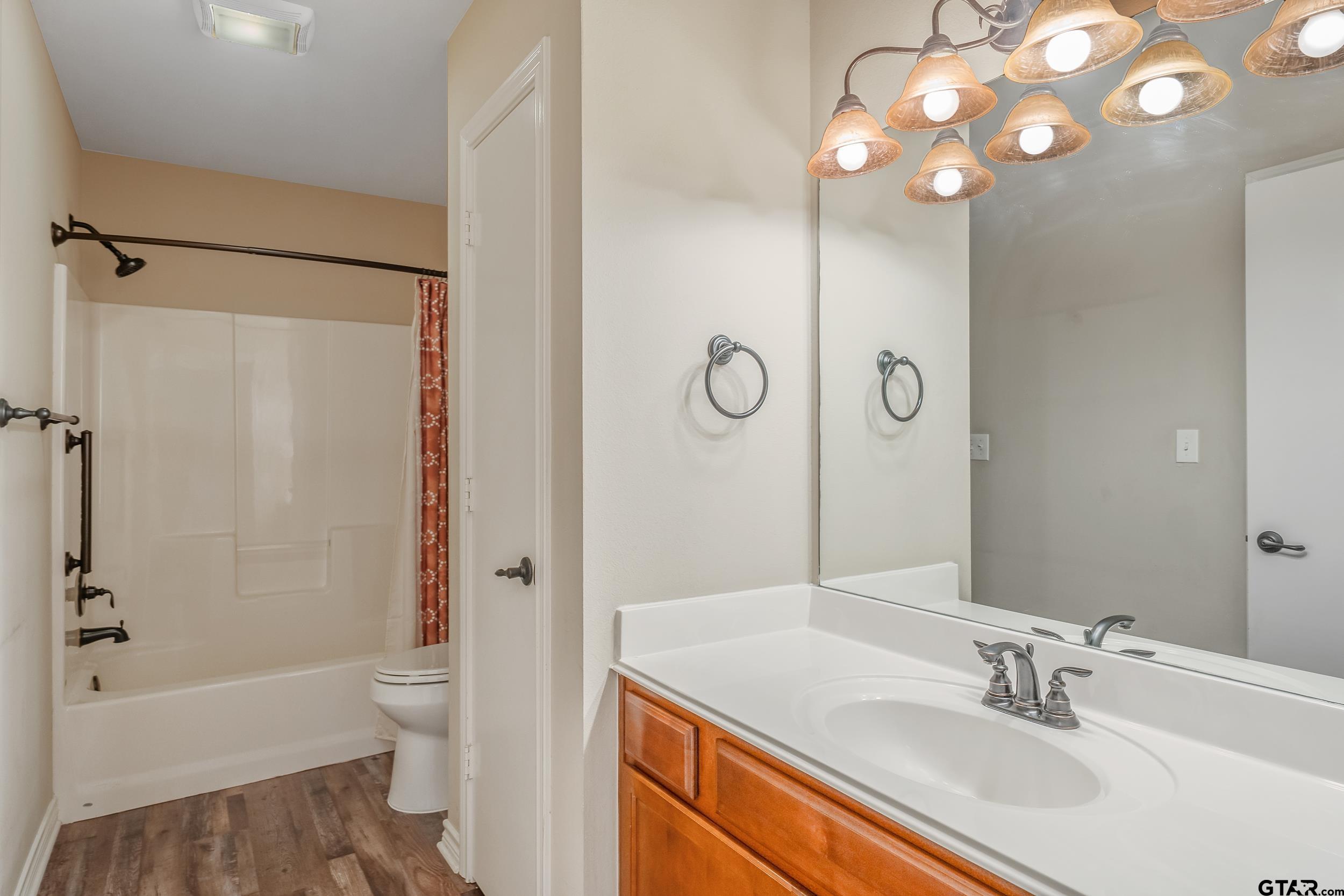 421 West Cumberland Road, Unit 205 Tyler, TX 75703 - Photo 13 of 24 a bathroom with a sink a toilet a mirror a bathtub and shower