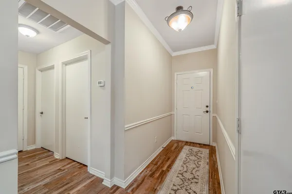 a view of an empty room with wooden floor and a ceiling fan