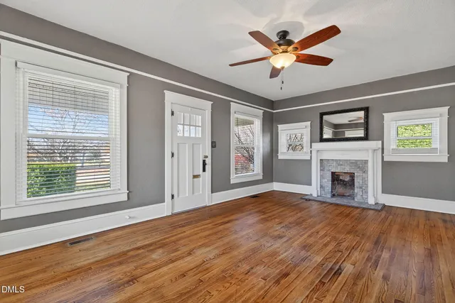 a view of an empty room with wooden floor and a window