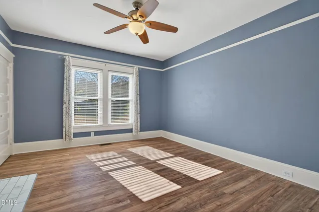 a view of an empty room with window and wooden floor