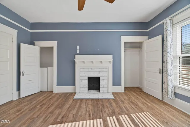 a view of a livingroom with a fireplace a ceiling fan and wooden floor