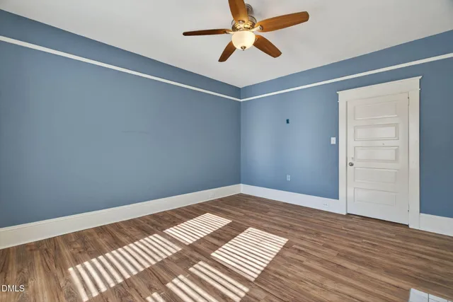 a view of empty room with wooden floor and fireplace