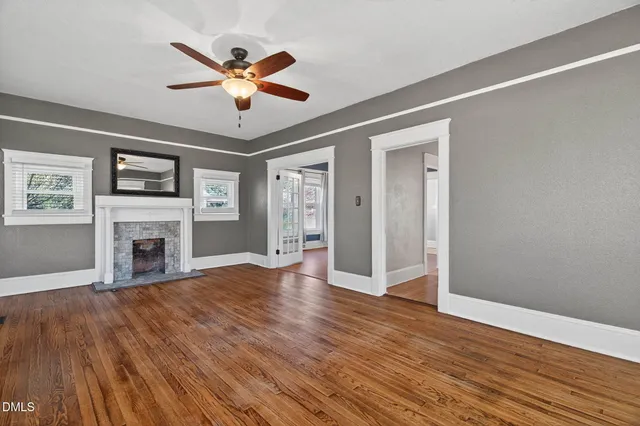 a view of a livingroom with wooden floor a ceiling fan and windows
