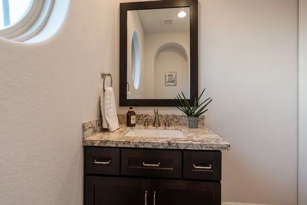 a bathroom with a granite countertop sink and a mirror
