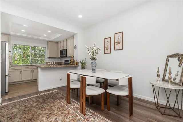 a kitchen with kitchen island a dining table chairs cabinets and stainless steel appliances