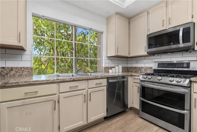 a kitchen with granite countertop a stove a sink and a microwave