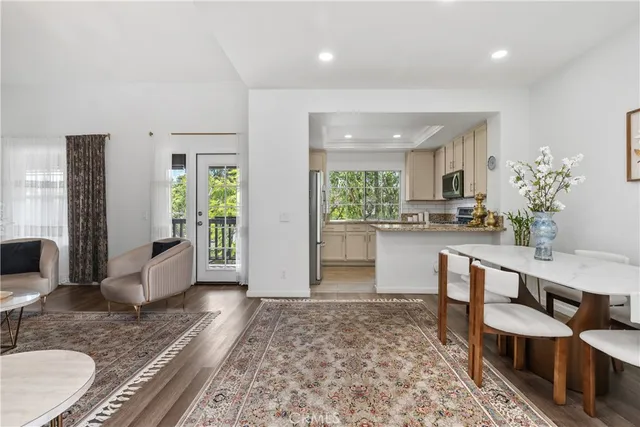 a large living room with stainless steel appliances granite countertop a couch and white cabinets with wooden floor