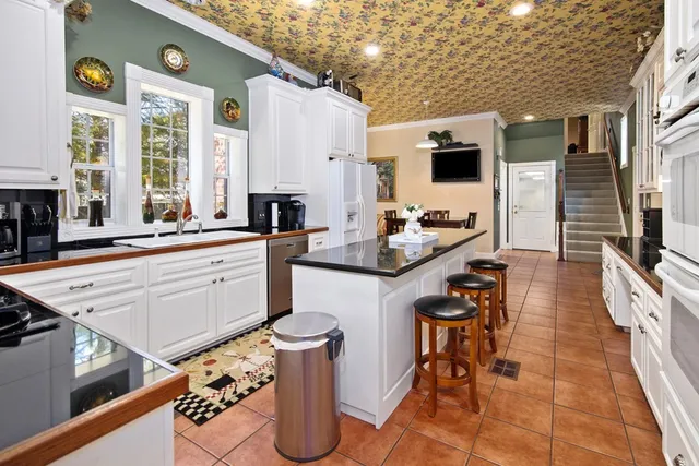 a large kitchen with a table chairs wooden cabinets and stainless steel appliances