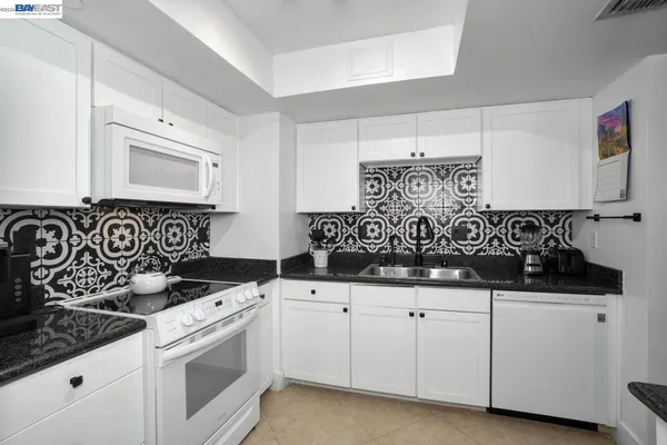a kitchen with white cabinets sink and white appliances