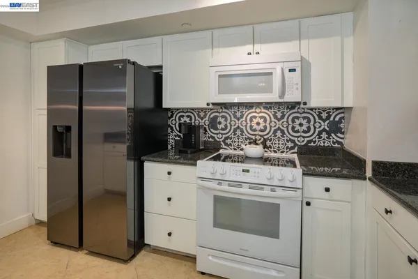 a kitchen with white cabinets and white appliances