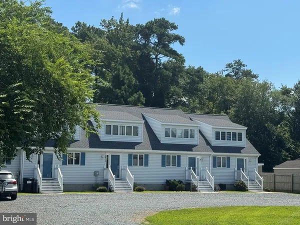 a front view of a house with garden and trees