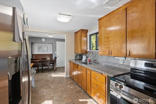 a kitchen with stainless steel appliances granite countertop a sink and a refrigerator