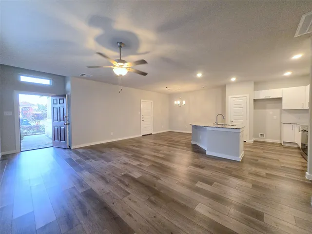 a view of an empty room with wooden floor and a ceiling fan