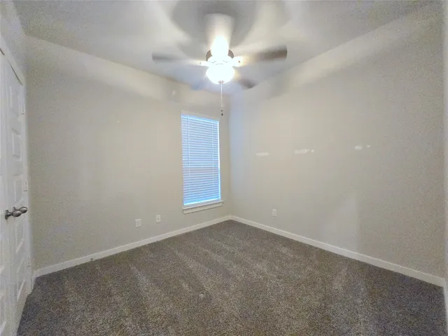 an empty room with a chandelier fan and windows