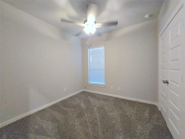 an empty room with a chandelier fan and windows