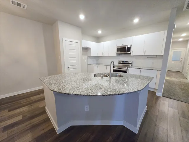 a kitchen with granite countertop a sink a counter top space stainless steel appliances and cabinets