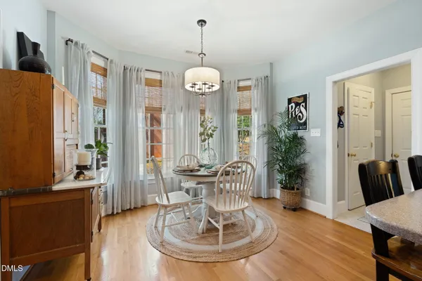 a kitchen with stainless steel appliances granite countertop a refrigerator a sink a stove a dining table and chairs