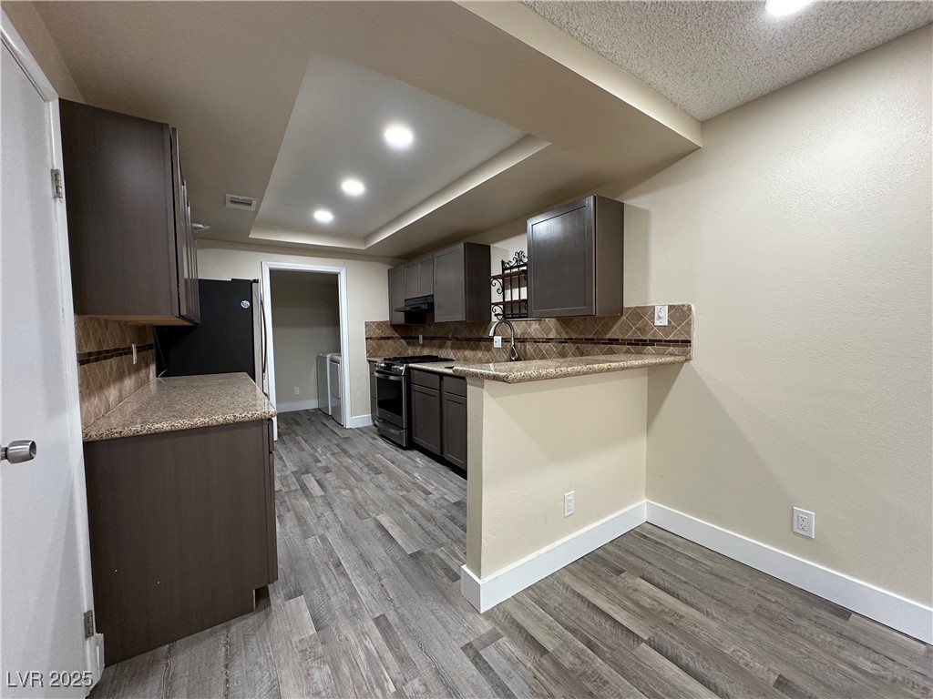117 Boysenberry Lane Henderson, NV 89074 - Photo 11 of 22 Kitchen featuring tasteful backsplash, light stone countertops, light wood finished floors, stainless steel appliances, and recessed lighting