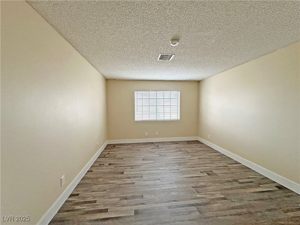 117 Boysenberry Lane Henderson, NV 89074 - Photo 15 of 22 Unfurnished room featuring light wood finished floors and a textured ceiling