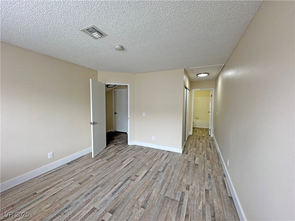 117 Boysenberry Lane Henderson, NV 89074 - Photo 19 of 22 Unfurnished bedroom with light wood-style floors and a textured ceiling