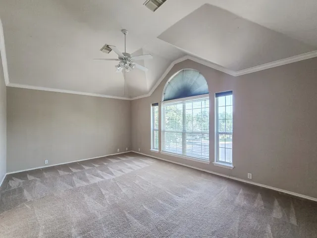 an empty room with windows and ceiling fan