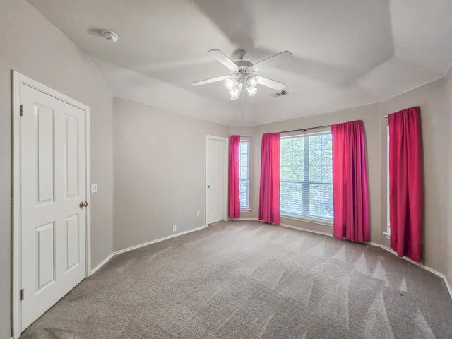 an empty room with windows and chandelier fan
